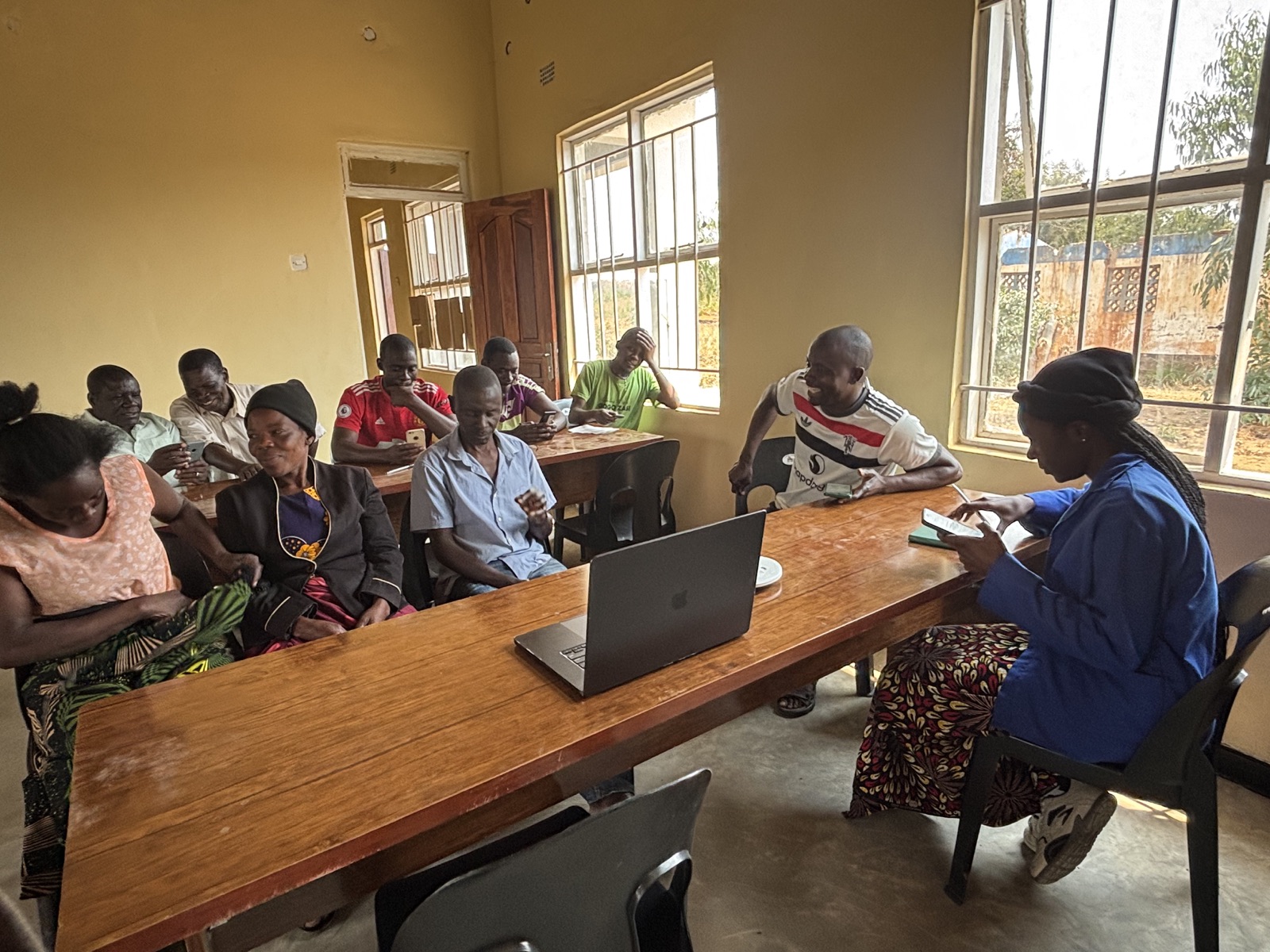 Computer literacy instruction with Kazuni participants around a laptop