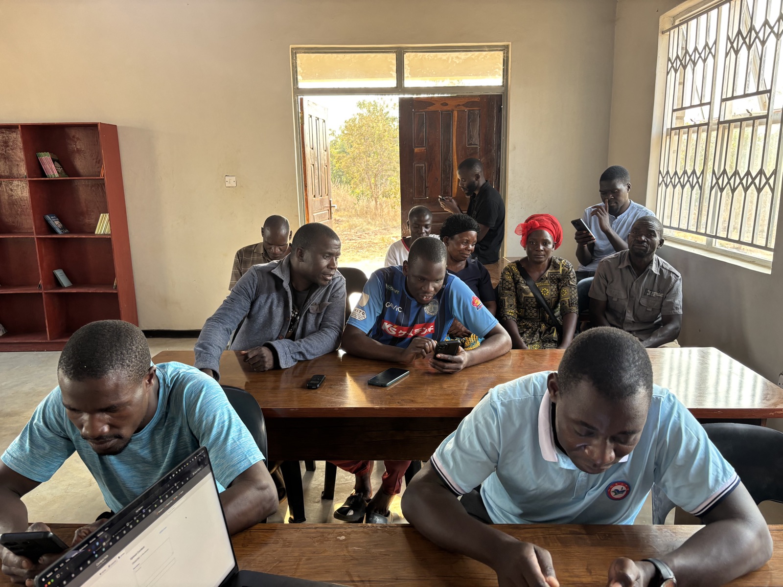 Participants following a RACHEL training session around a laptop in Thunduwike